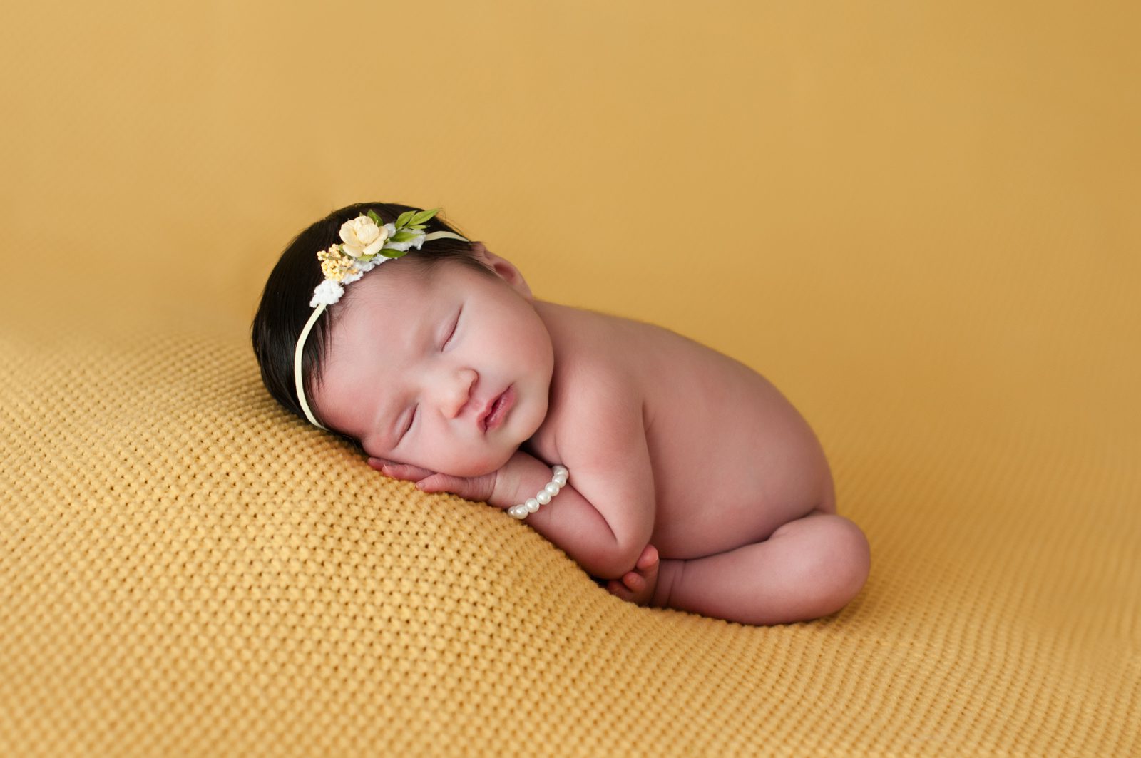 Sleeping naked baby on yellow blanket with flower headband by South Florida newborn photographer