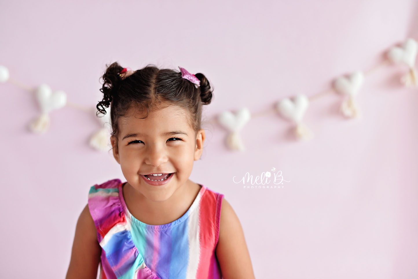 A toddler girl in photo session smiling naturally at camera