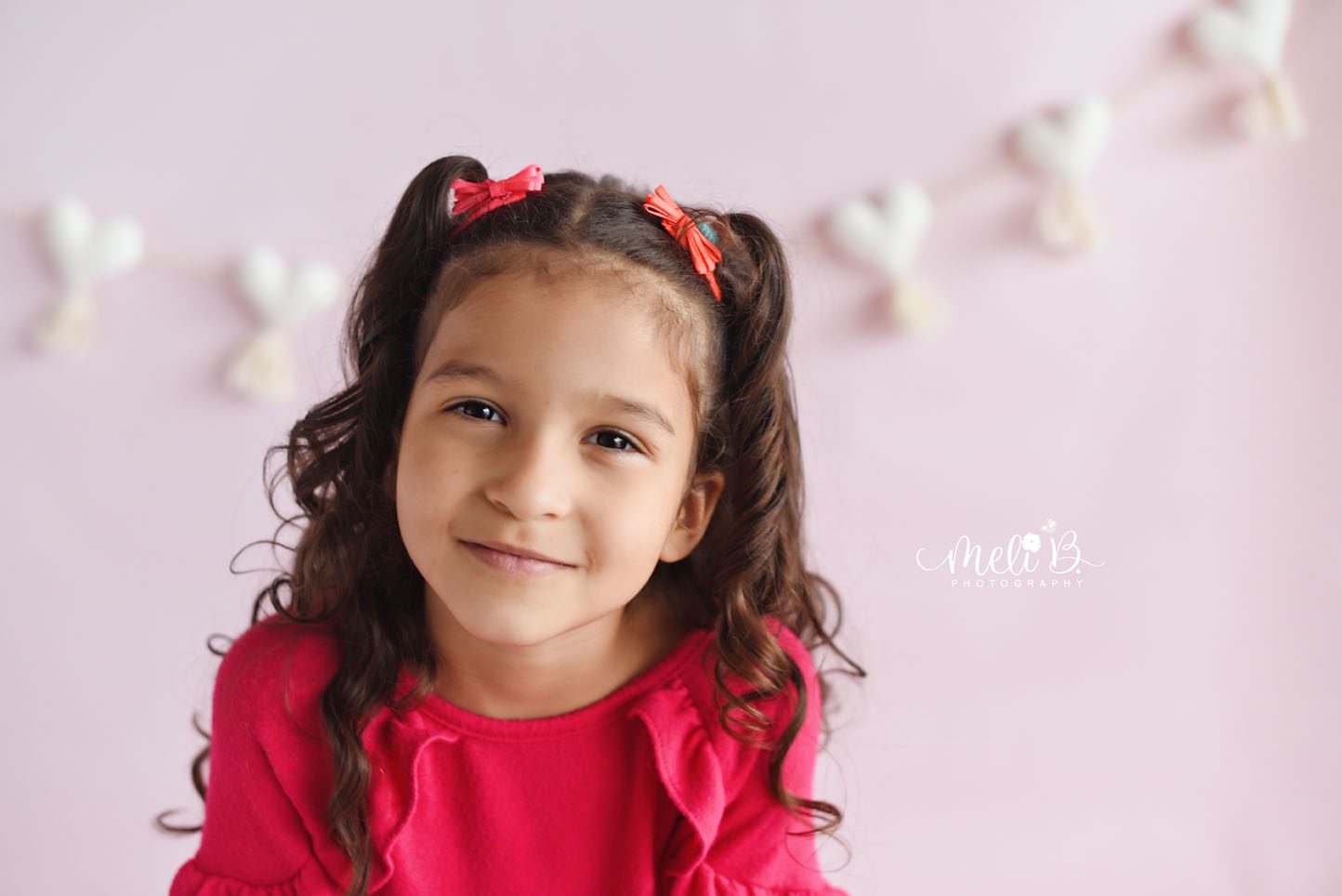 child close up in photo session smiling with pink background and white hearts