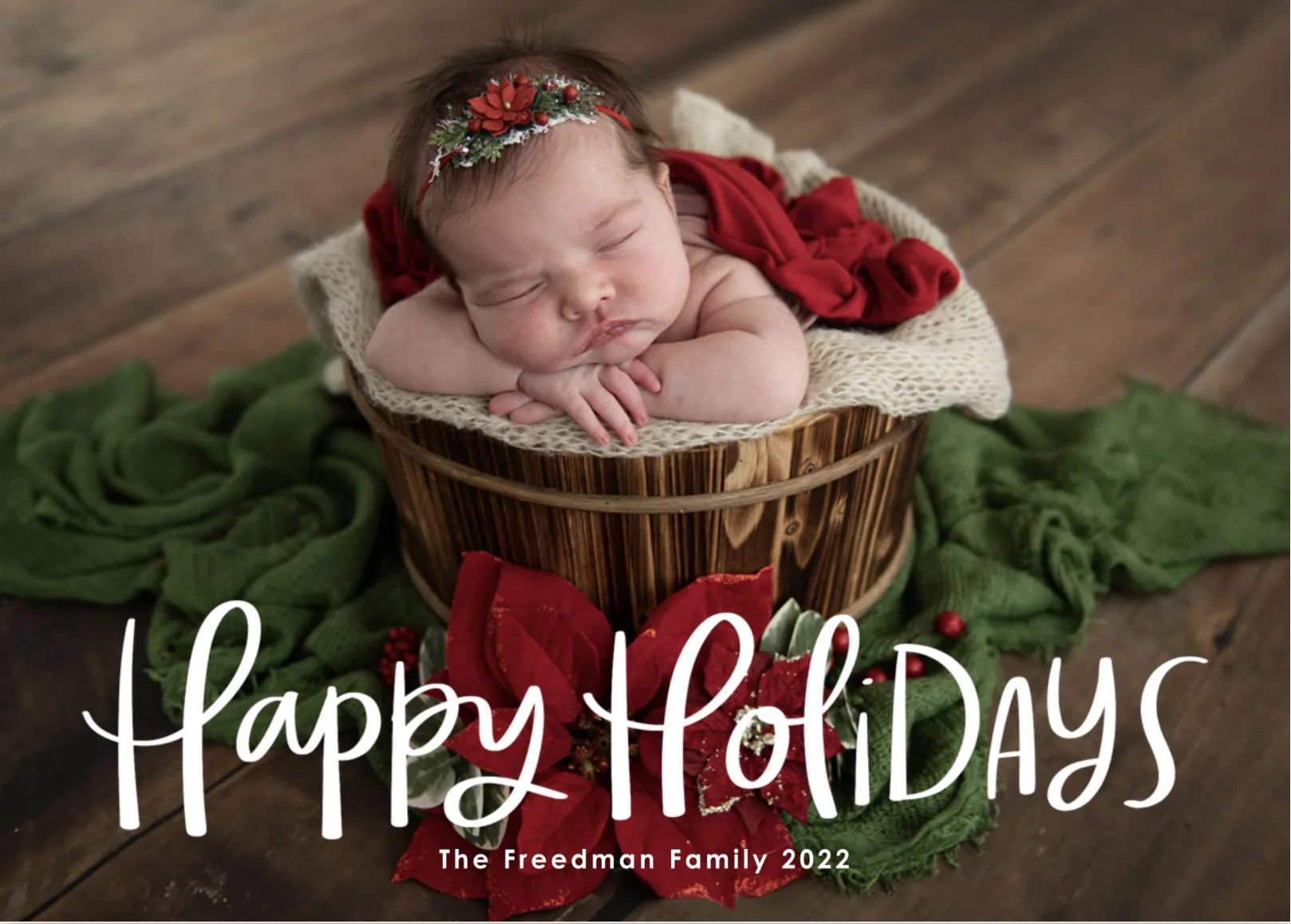 A baby sleeping in a basket with the words happy holidays on a card