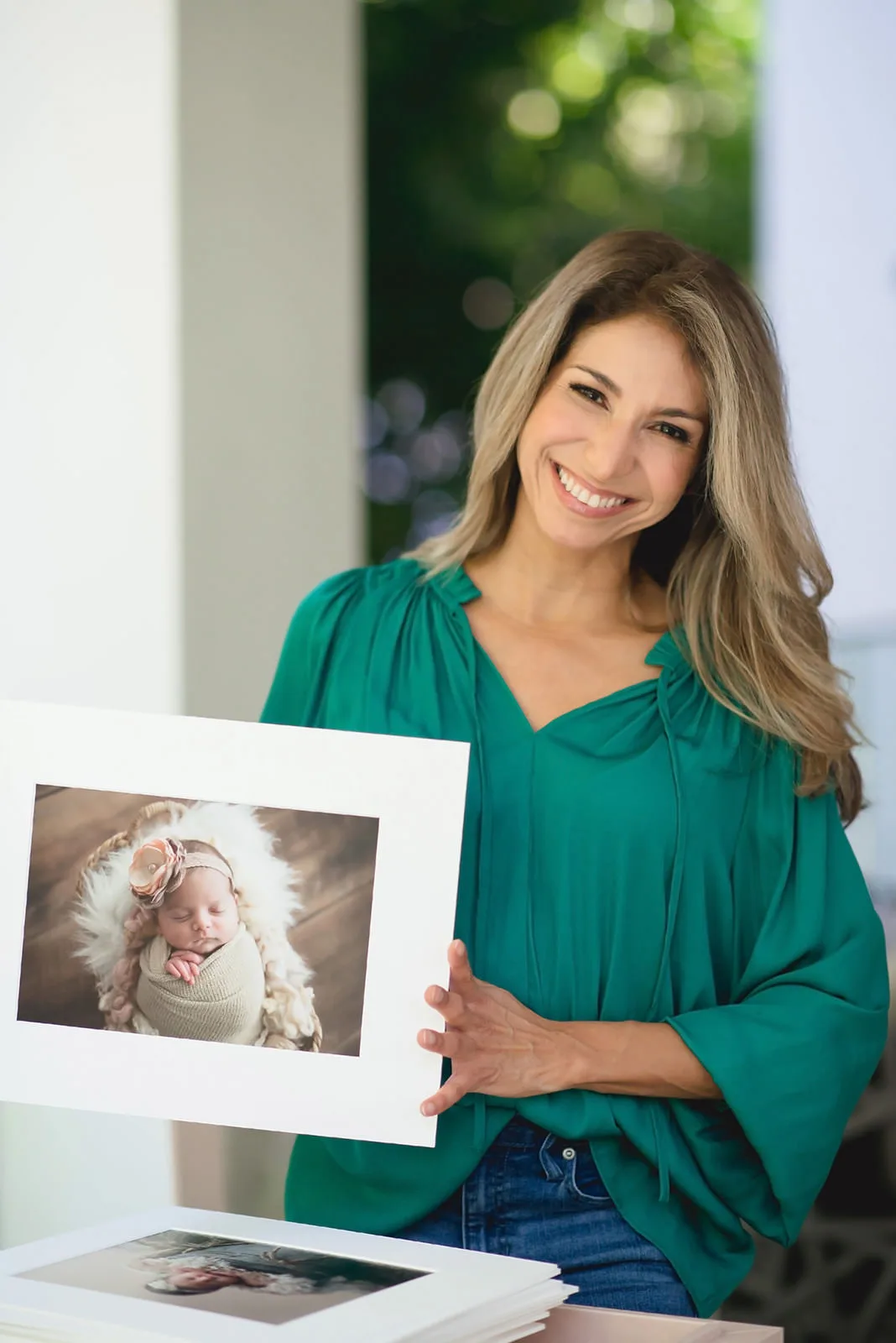 Miami Photographer MeliB holding up a photo of a newborn baby.