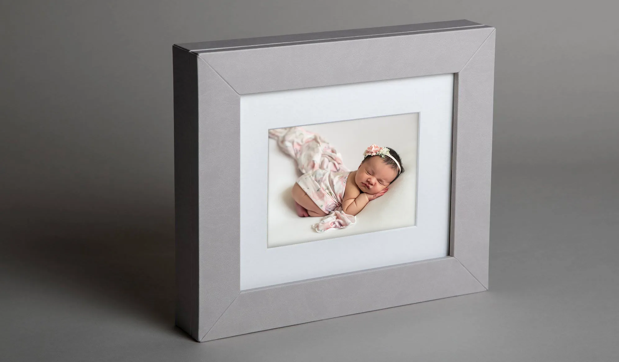 A grey frame with a photo of a baby in it.