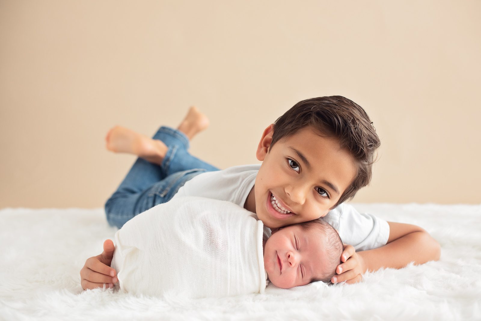 Brother posing with smiling baby for South Florida Newborn Photography session